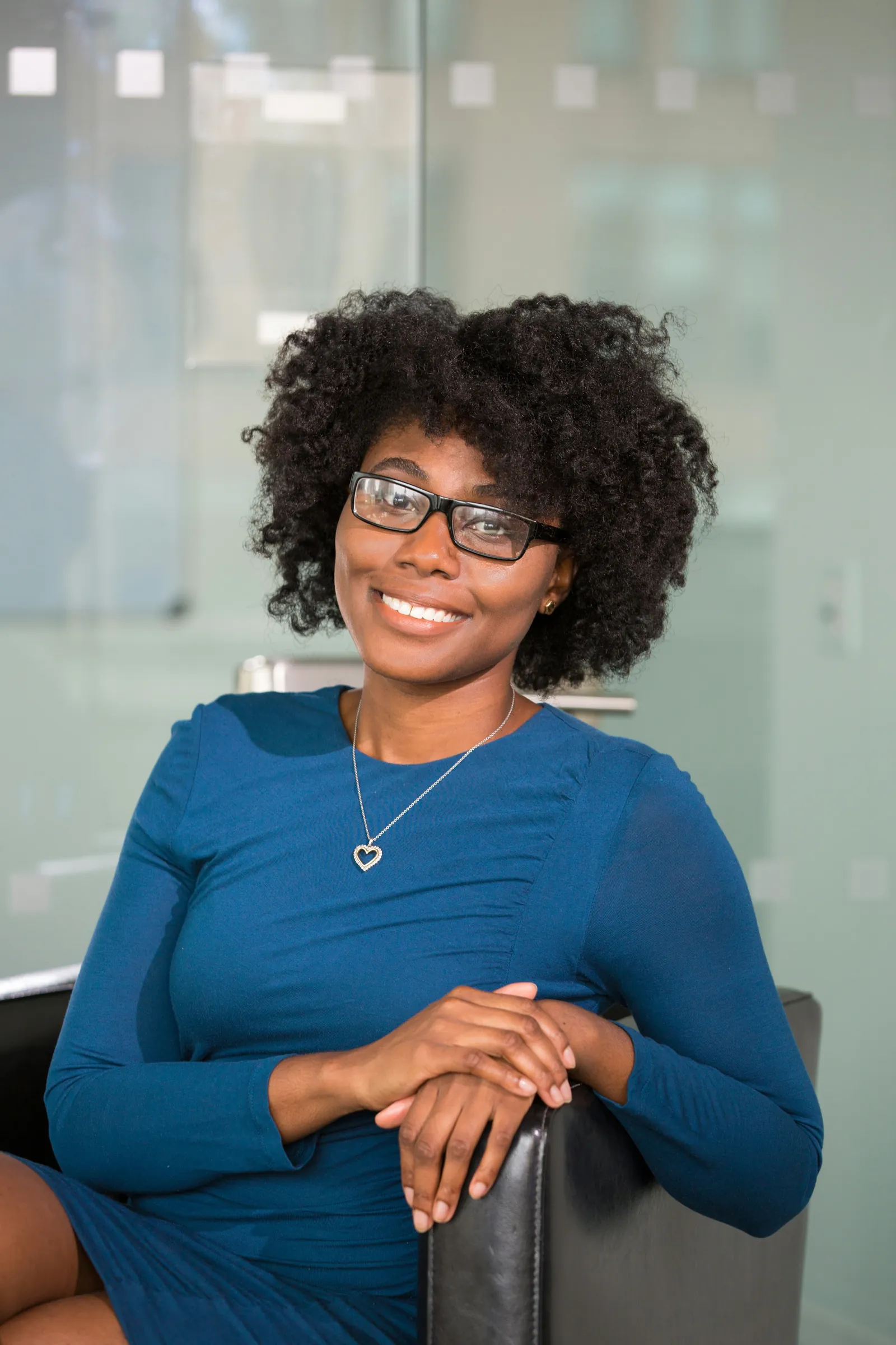 A smiling professional woman in glasses seated in a bright office